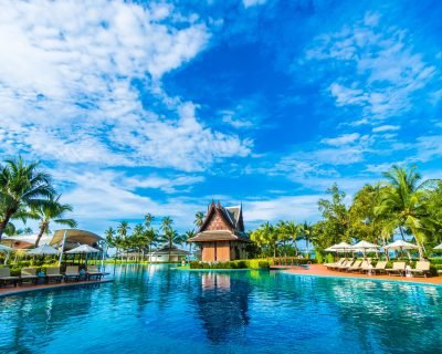 Beautiful luxury umbrella and chair around outdoor swimming pool in hotel and resort with coconut palm tree on blue sky - Boost up color Processing